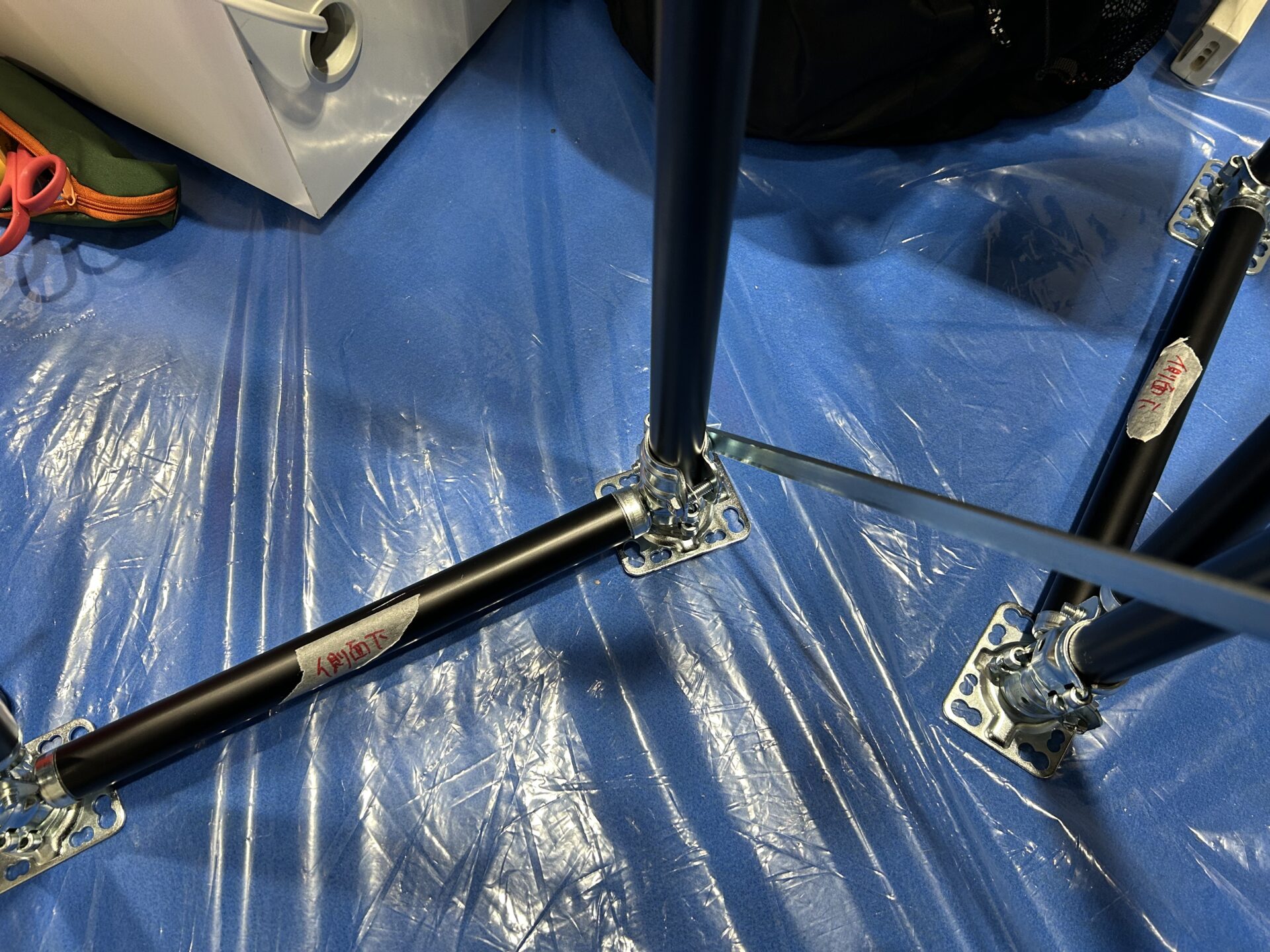 パイプに側面下と書いたマスキングテープを貼っている